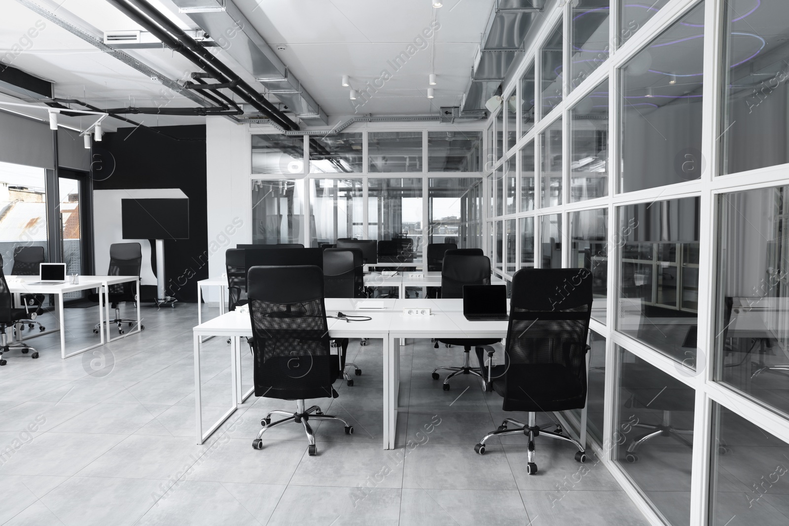 Photo of Stylish interior of open plan office. Workspace with computers, tables and chairs