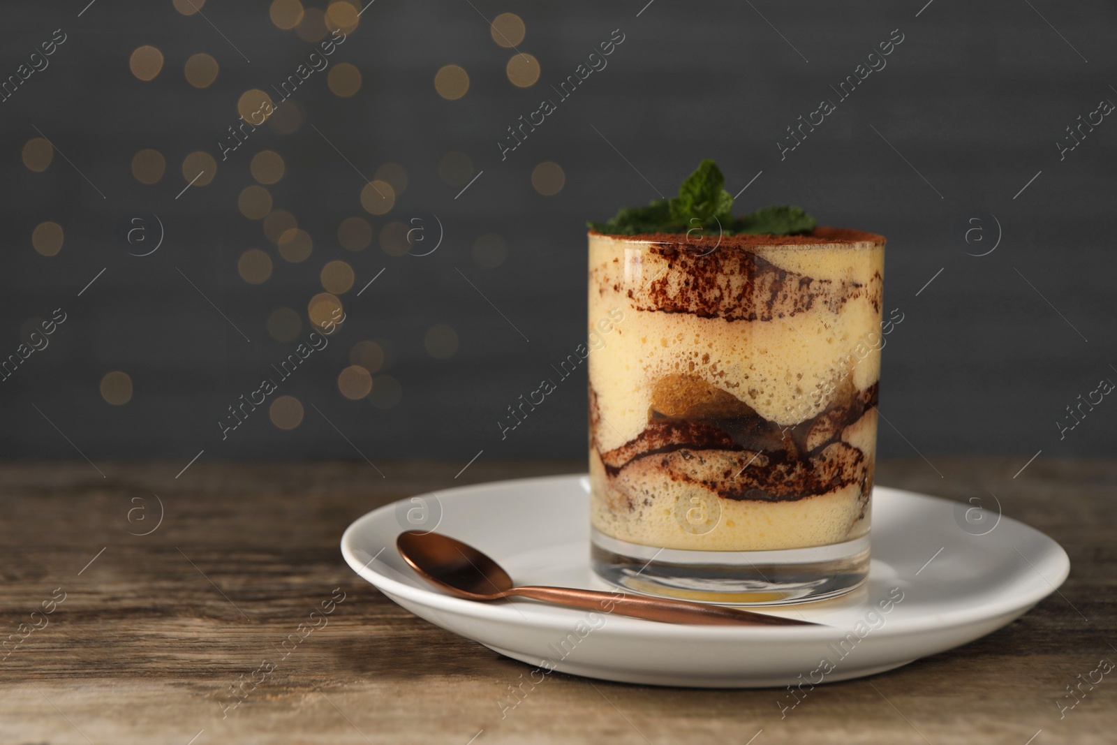 Photo of Tasty tiramisu and mint in glass on wooden table, space for text