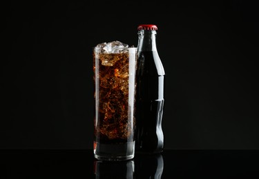 Photo of Bottle and glass of refreshing soda water on black background