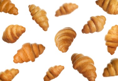 Crusty golden croissants falling on white background