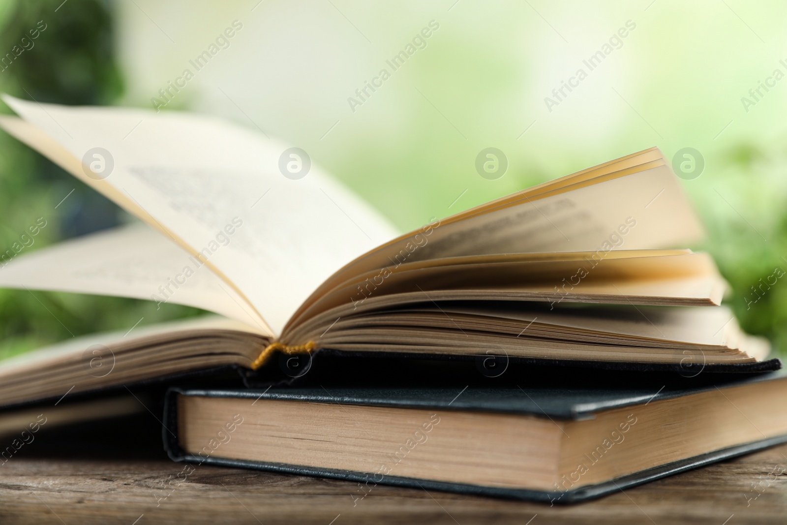 Photo of Open hardcover book on wooden table against blurred background, closeup