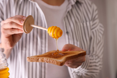 Photo of Woman pouring honey onto toasted bread, closeup