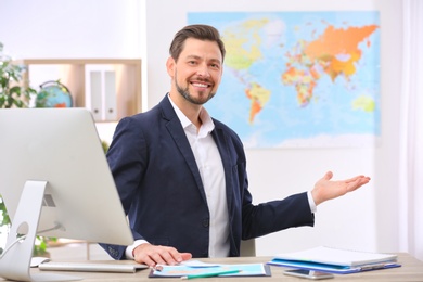 Photo of Male consultant sitting at table in travel agency