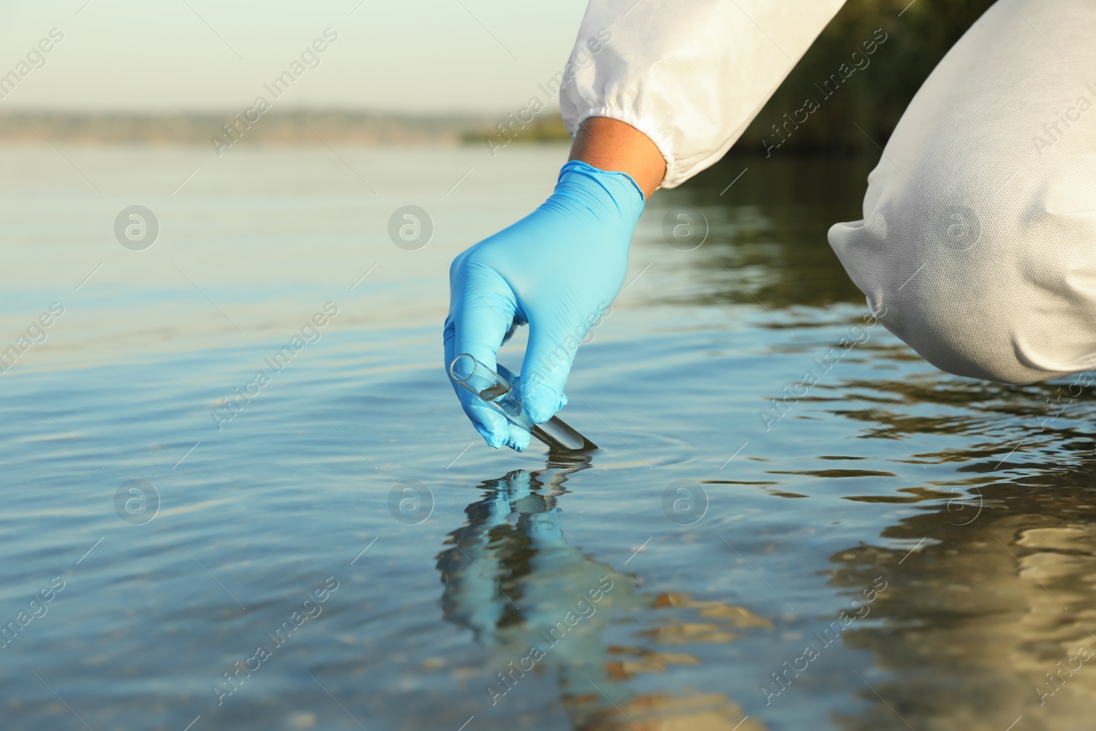 Photo of Scientist with test tube taking sample from river for analysis, closeup