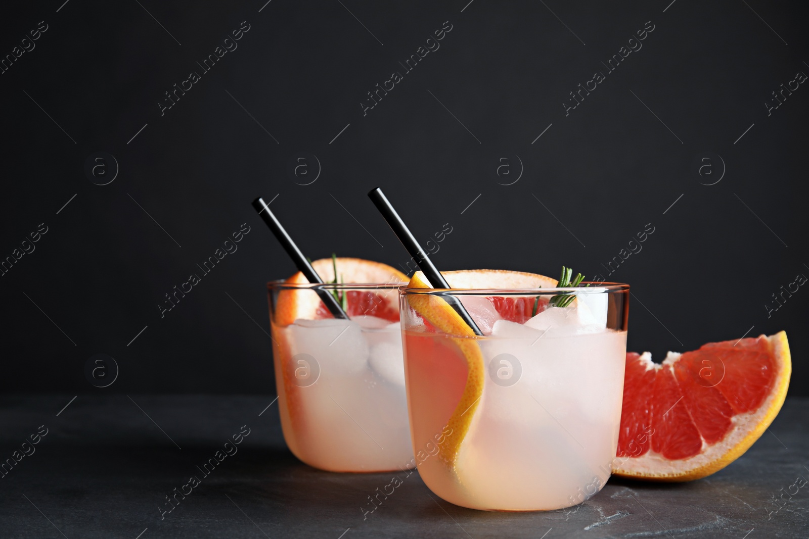 Photo of Glasses of cocktail and grapefruit slice on table. Space for text