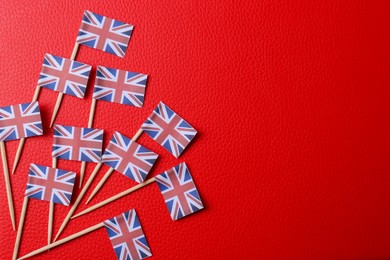 Photo of Small paper flags of United Kingdom on red textured background, flat lay. Space for text