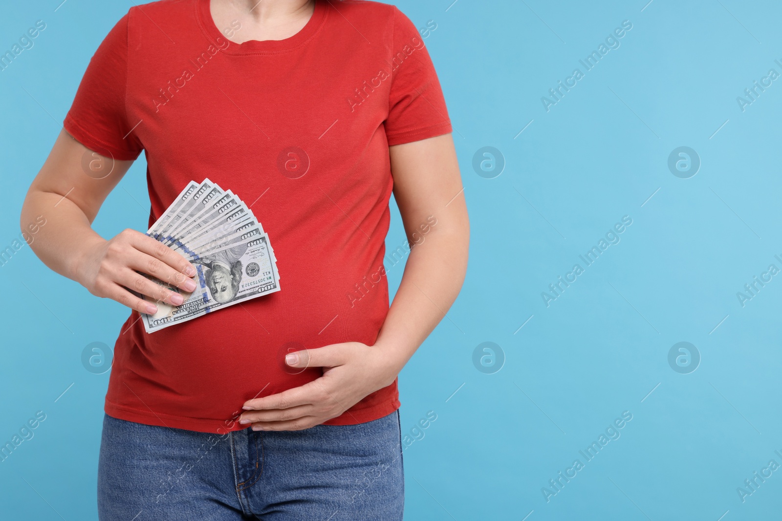 Photo of Surrogate mother. Pregnant woman with dollar banknotes on light blue background, closeup. Space for text