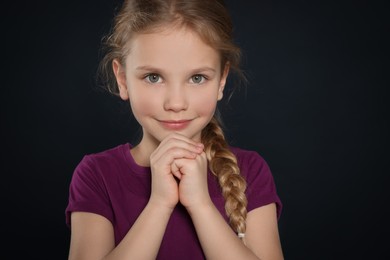Photo of Girl with clasped hands praying on black background