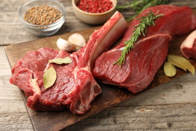 Pieces of raw beef meat and spices on wooden table