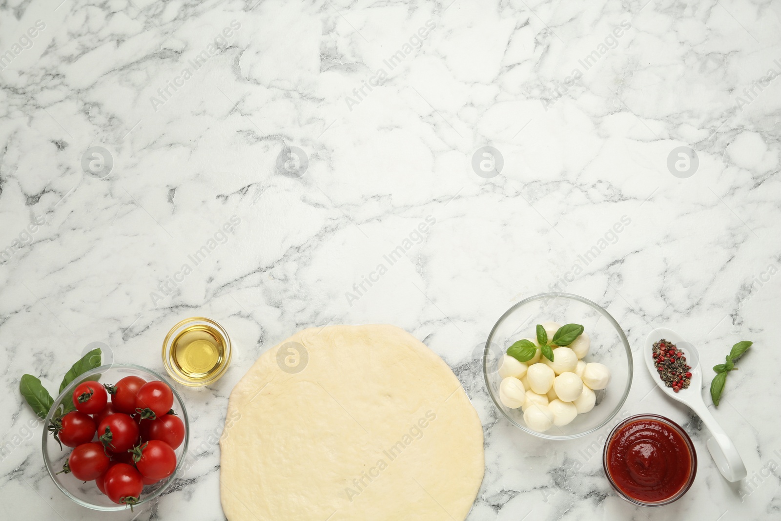 Photo of Raw pizza dough and other ingredients on white marble table, flat lay. Space for text