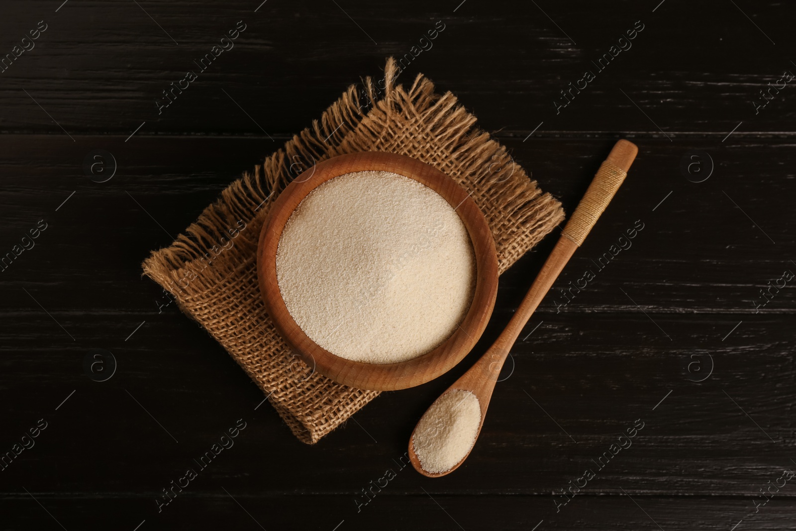 Photo of Fresh semolina on black wooden table, flat lay