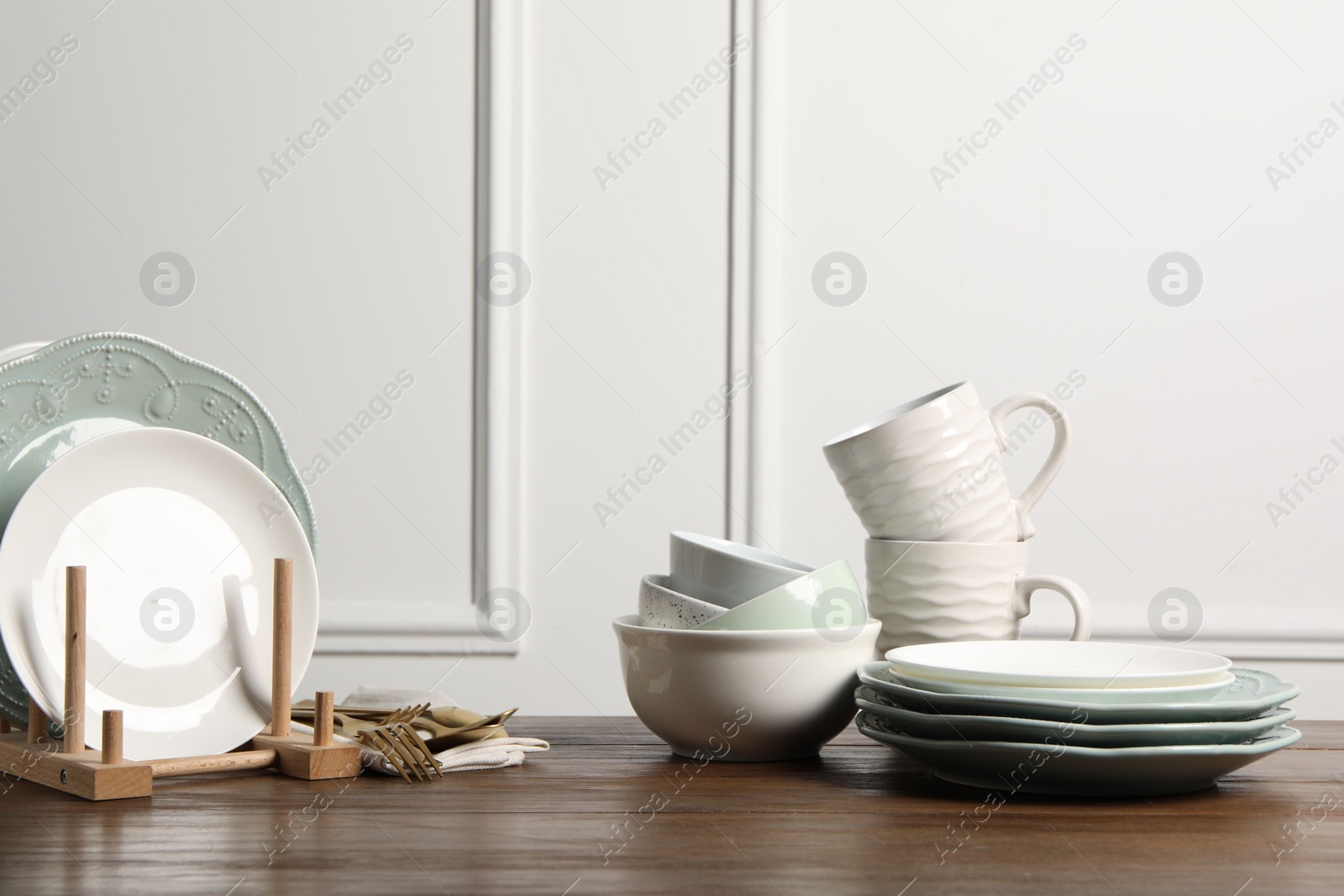 Photo of Beautiful ceramic dishware, cups and cutlery on wooden table