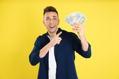 Photo of Emotional man with cash money on yellow background