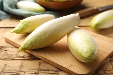 Photo of Fresh raw Belgian endives (chicory) on wooden table, closeup