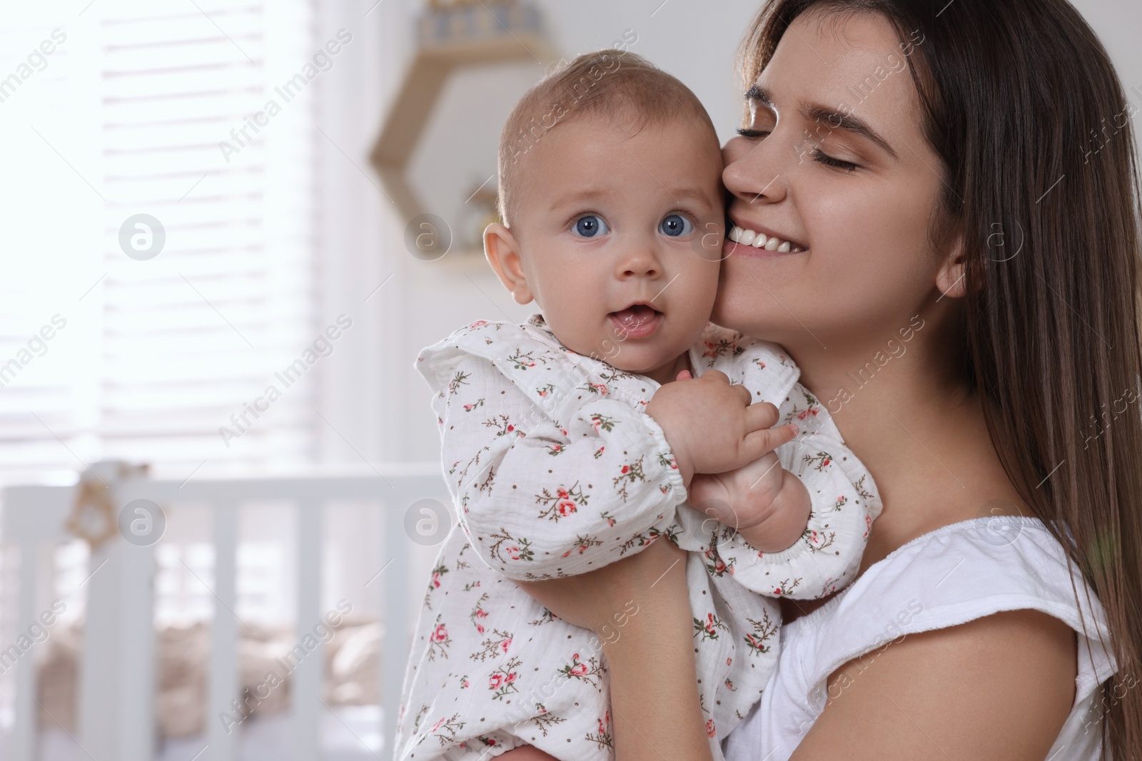 Photo of Happy young mother with her baby daughter in nursery. Space for text