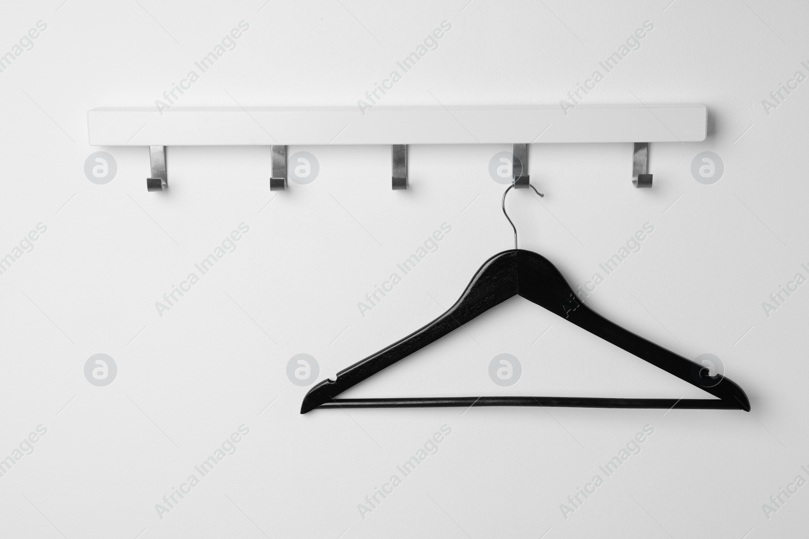 Photo of Rack with empty black clothes hanger on white wall