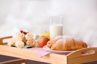 Photo of Tray with delicious croissants, milk and apples indoors
