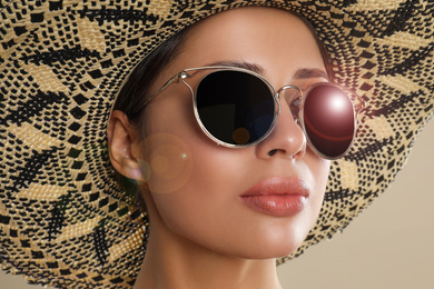 Image of Beautiful young woman wearing sunglasses and hat on beige background, closeup