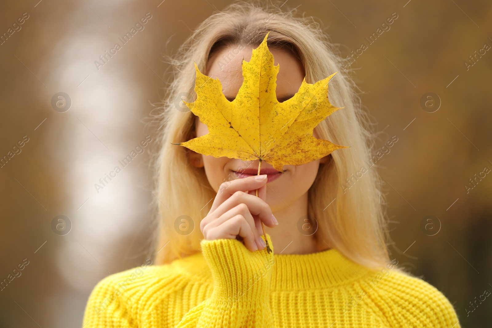 Photo of Woman covering face with autumn leaf outdoors