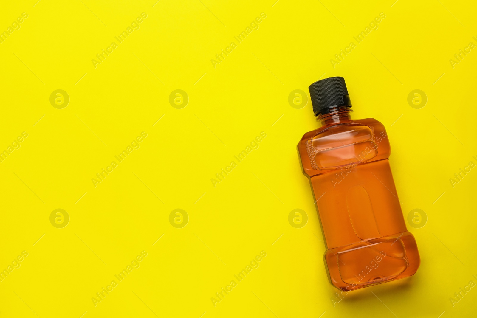 Photo of Mouthwash on yellow background, top view. Space for text