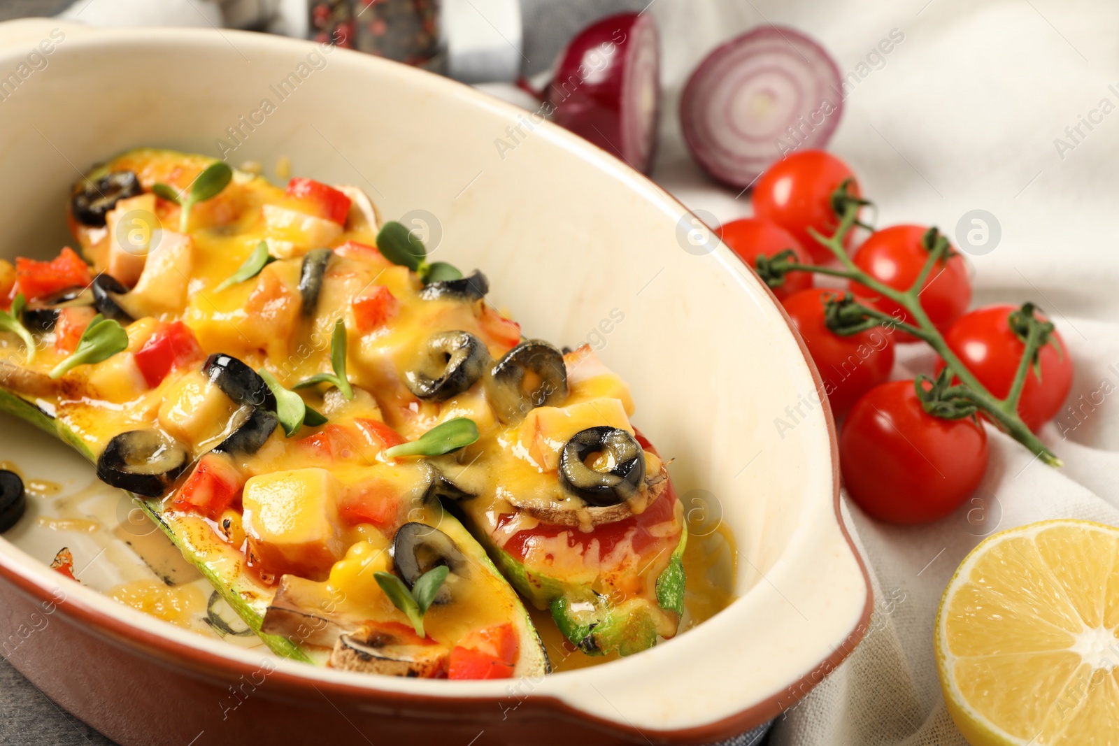 Photo of Baking dish with delicious stuffed zucchinis and fresh ingredients, closeup