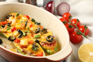 Photo of Baking dish with delicious stuffed zucchinis and fresh ingredients, closeup