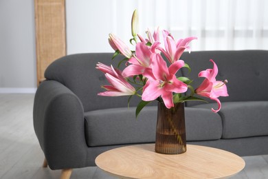 Beautiful pink lily flowers in vase on wooden table indoors, space for text