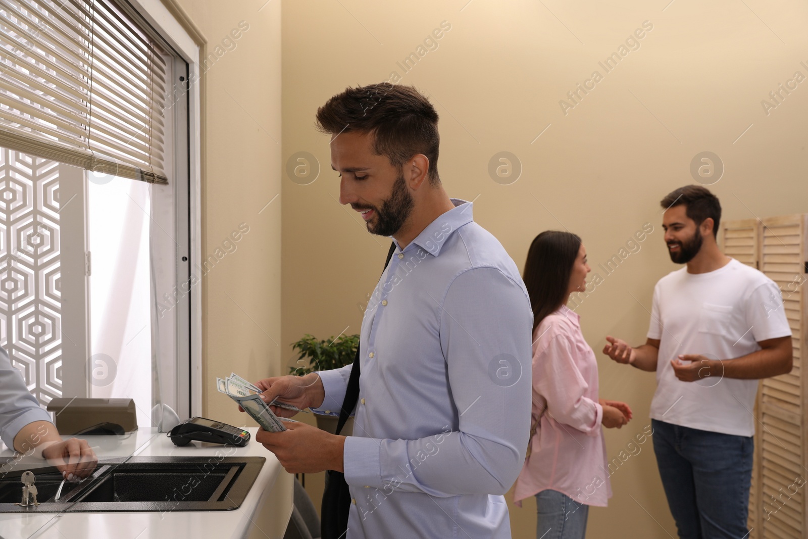 Photo of Man with money at cash department window in bank. Currency exchange