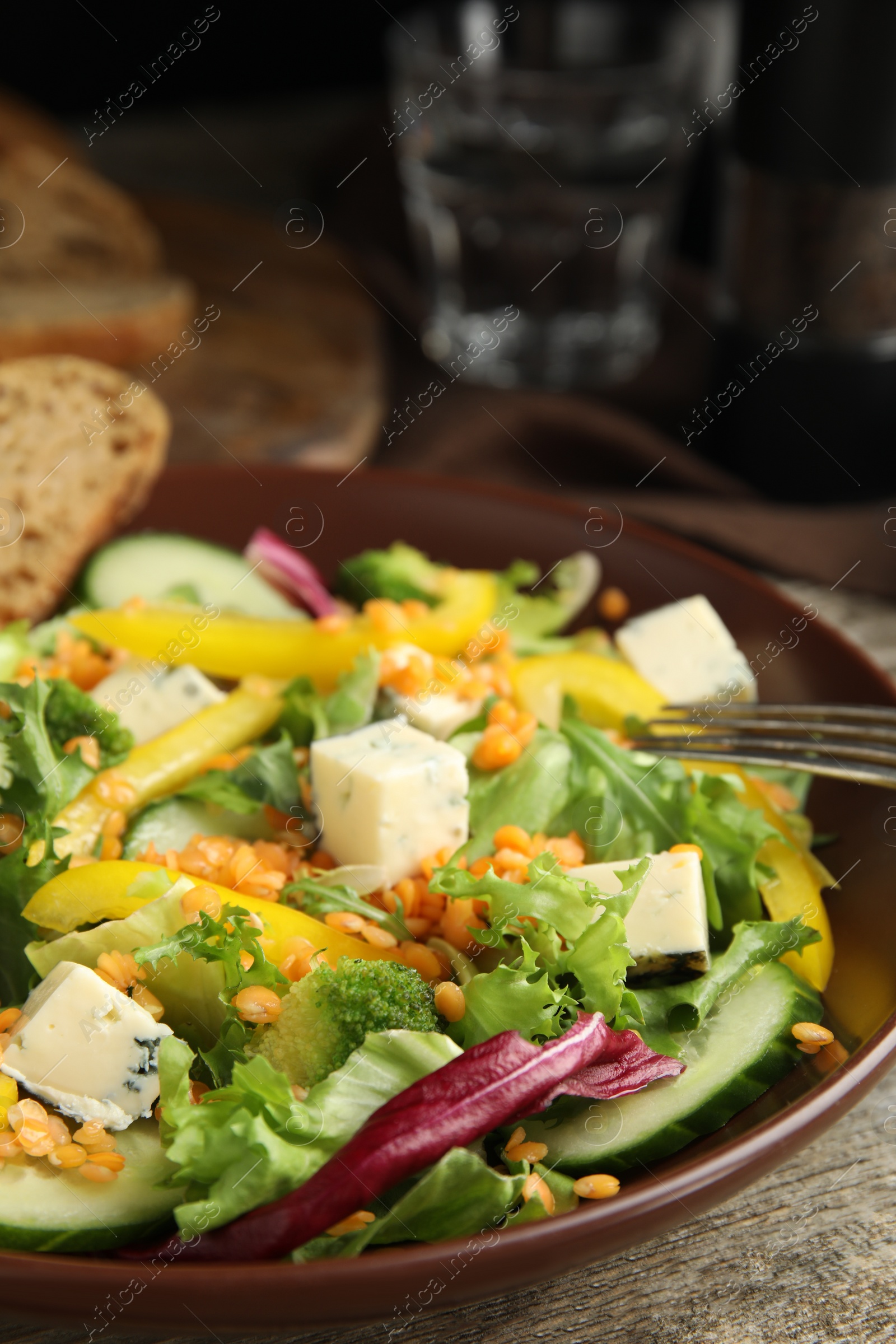 Photo of Delicious salad with lentils, vegetables and cheese on wooden table, closeup