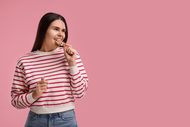 Photo of Young woman with chocolate chip cookie on pink background, space for text