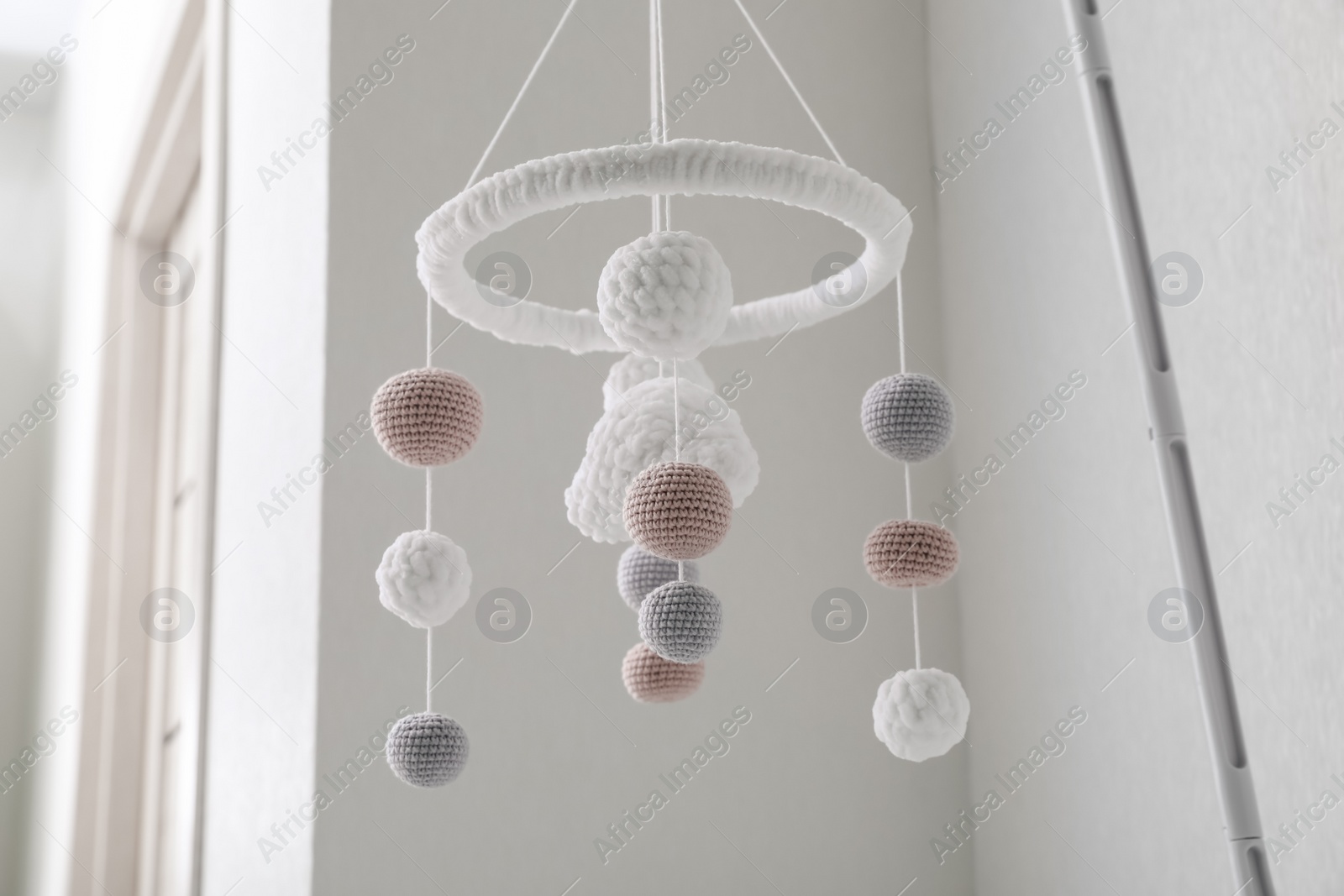 Modern baby crib mobile near beige wall in room, low angle view Photo of Modern baby crib mobile near beige wall in room, low angle view