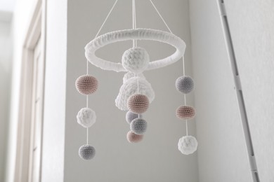 Photo of Modern baby crib mobile near beige wall in room, low angle view