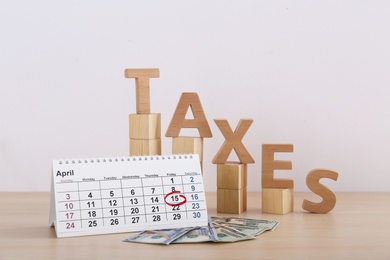 Photo of Word TAXES, money and calendar on table