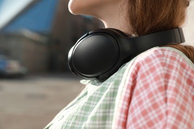Woman with headphones outdoors, closeup. Space for text