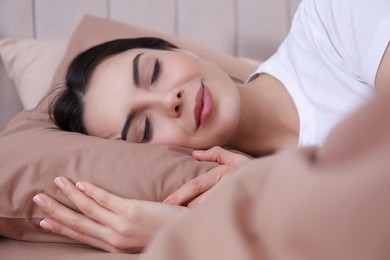 Woman sleeping in comfortable bed with beige linens
