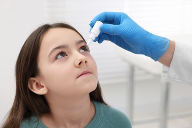 Photo of Doctor applying medical drops into girl's eye indoors