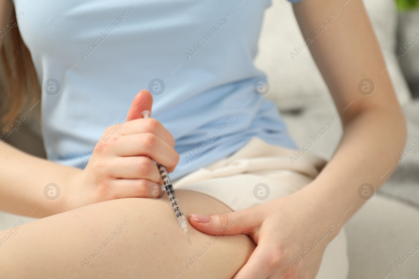 Photo of Diabetes. Woman making insulin injection into her leg indoors, closeup