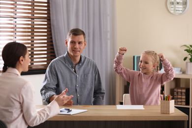 Photo of Child psychotherapist working with little girl and her father in office
