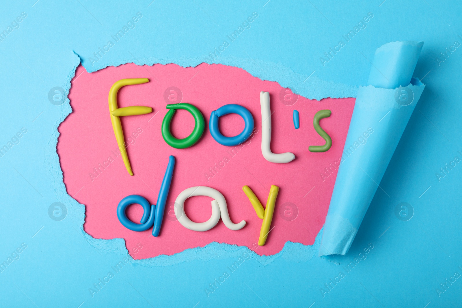 Photo of Flat lay composition with words FOOL'S DAY made of clay on color background. April holiday