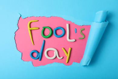 Photo of Flat lay composition with words FOOL'S DAY made of clay on color background. April holiday