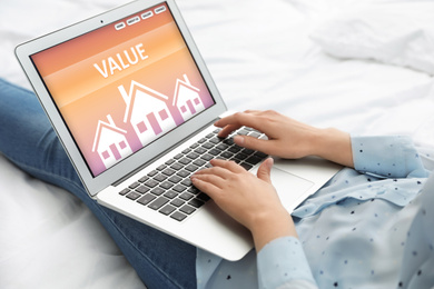 Image of Property value concept. Woman working with laptop on bed, closeup