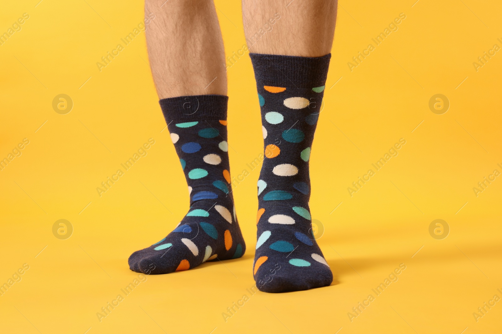 Photo of Man in stylish colorful socks on yellow background, closeup