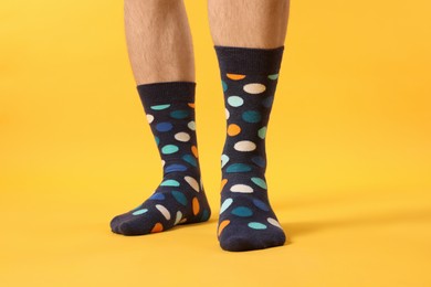 Man in stylish colorful socks on yellow background, closeup