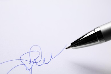 Photo of Signing on sheet of white paper with pen, closeup