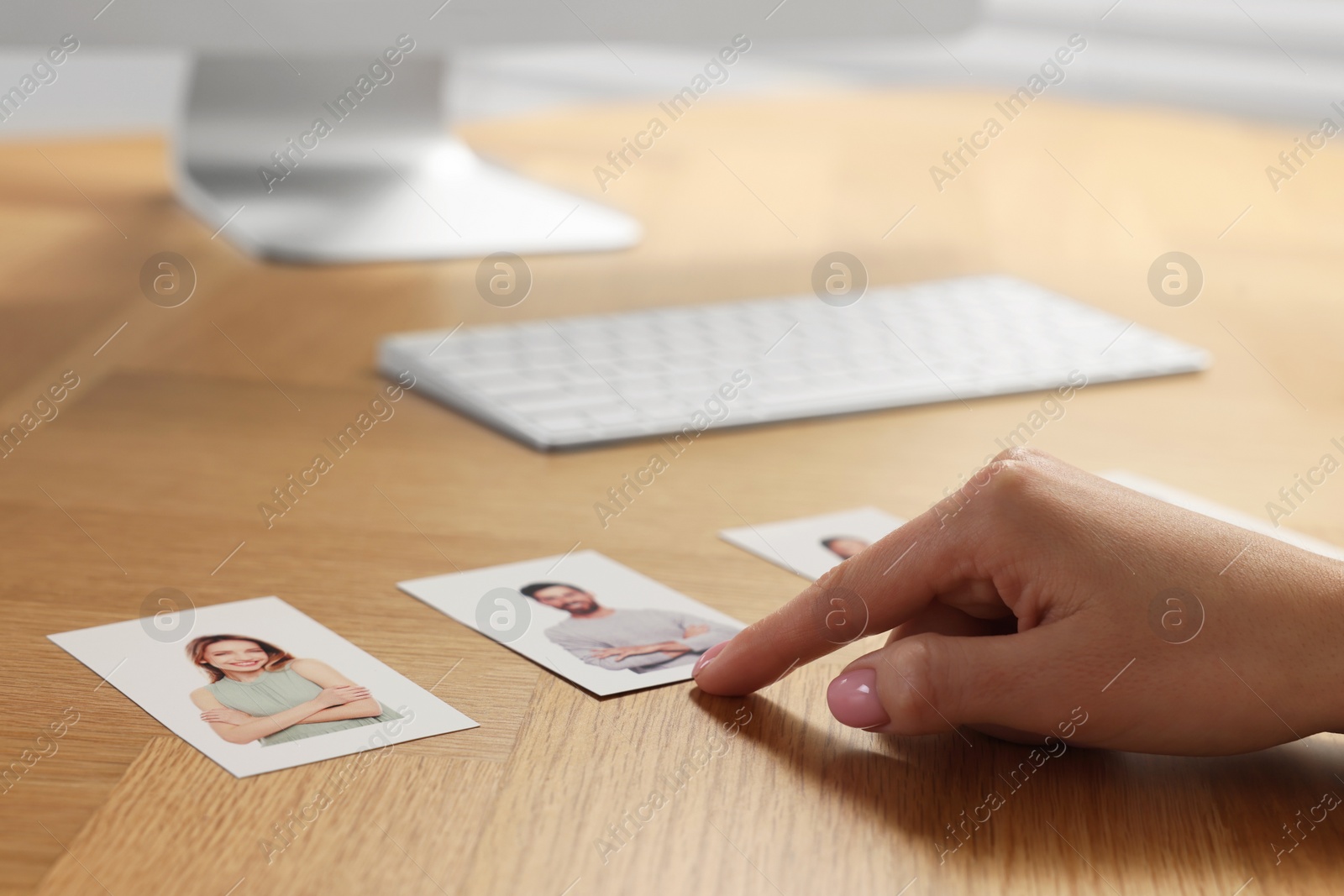 Photo of Human resources manager choosing employee among different applicants at wooden table, closeup