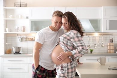 Photo of Pregnant woman with her husband in kitchen. Happy young family