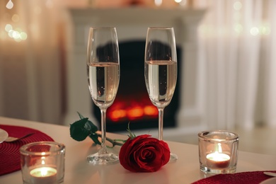 Photo of Romantic table setting with champagne, rose and candles for Valentine's day dinner indoors