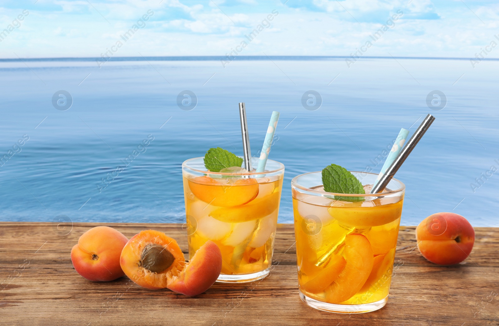 Image of Tasty refreshing drink on wooden table against sea