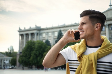 Photo of Handsome man talking on smartphone on city street