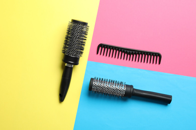 Photo of Hair brushes and comb on color background, flat lay